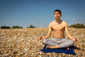 Fototapeta na wymiar Teenage boy on a beach meditating