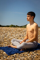 Fototapeta na wymiar Teenage boy on a beach meditating