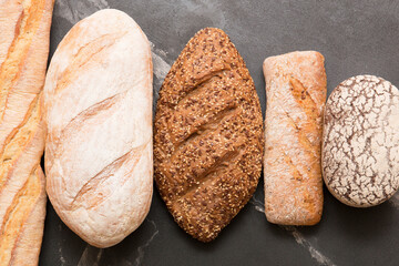 Bread, pastries on a dark background. Bread with sesame seeds and seeds, bread texture. Delicious flavored bun. Lots of airy fresh bread.