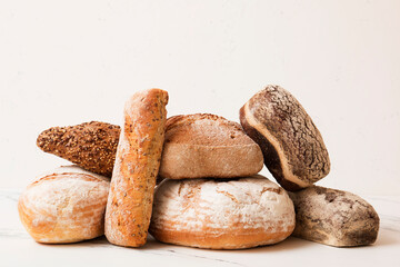 Bread, pastries on a light background. Bread with sesame seeds and seeds, bread texture. Delicious flavored bun. Lots of airy fresh bread.