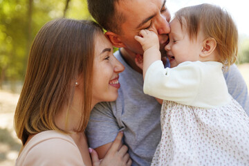 Happy young family spending time together, mother and father with baby outside in green nature.