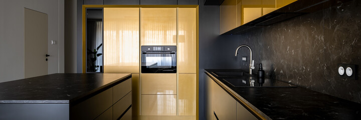 Modern black and gold kitchen with kitchen island, panorama