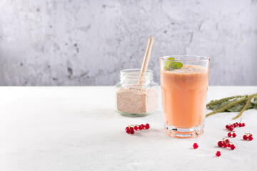 a glass of smoothies made of red currant berries and coconut milk with the husk of plantain seeds ....