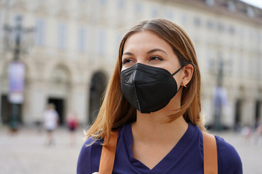 Portrait of student girl wearing a protective KN95 FFP2 black mask walking in city street