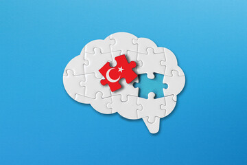 Turkish learning concept, white jigsaw puzzle pieces with turkish flag a human brain shape on blue...