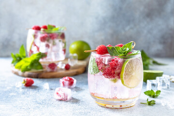 Hard seltzer cocktail with raspberries and lime on a gray stone table top. Copy space.