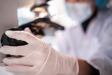 Fototapeta premium scientist looking through scientific microscope lense in laboratory, scientist doing research in term of medicine biotechnology biology or chemistry, doctor analyzing work in medical microbiology lab