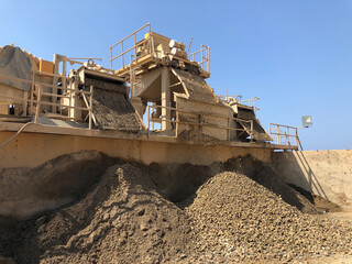Different sized crushed stone fall out of stone crashing machine. Producing of construction materials at construction site