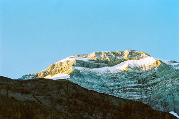 blue sky with no clouds. alpine summit covered with snow. sunrise on the mountains in swiss. hiking during summer holidays.