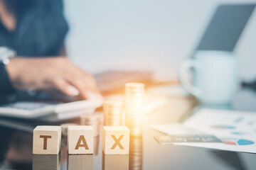 business man at the desk in the office Show a wooden cube with the word tax on corporate business...