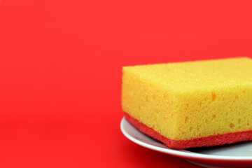 Yellow sponge on a white plate, red background