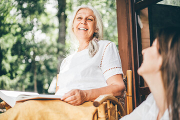Adult woman and senior mother talking on front porch