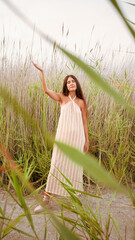young woman in striped dress with straps and halter neckline dances in the field
