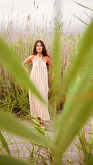 young woman in striped dress with straps and halter neckline posing in the field