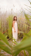 young woman in striped dress with straps and halter neckline posing in the field