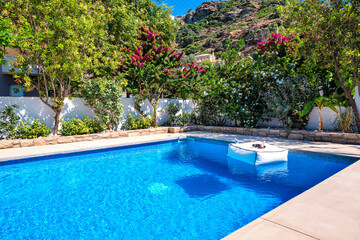 Pool area of a house or villa, with private swimming pool and greenery around.