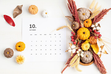 Flat lay with calendar for october with autumn table decoration.  Floral interior decor for fall holidays with handmade pumpkins. Flatlay, top view