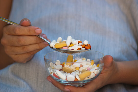 Taking medications. Taking medication with a tablespoon from a glass