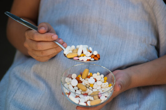 Taking medications. Taking medication with a tablespoon from a glass
