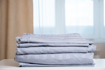 Motion down along high stack of light purple contemporary clean folded ironed linens lying on white...