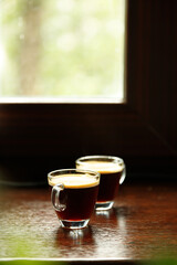 two glass coffee cup with espresso near the window with green in morning