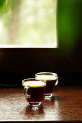 two glass coffee cup with espresso near the window with green in morning