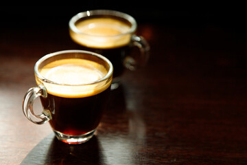 two glass coffee cup with espresso near the window in morning on dark background