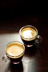 two glass coffee cup with espresso near the window in morning on dark background