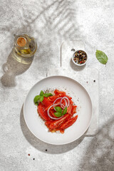 Salad with tomatoes and basil with oil in bottle on white board on white background