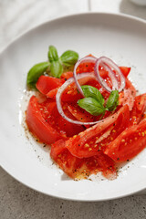 Salad with tomatoes and basil with oil in bottle on white board on white background