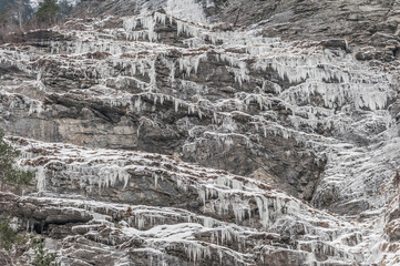 Sehr viele Eiszapfen an einer Felswand, von unten