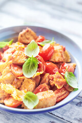Farfalle pasta with chicken breast, cherry tomatoes and fresh basil. Bright wooden background. Close up. 