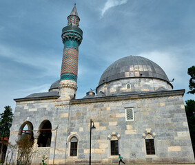 Green mosque (yesil camii) in Nicaea (iznik) during spring and sunny day in center of the city covered by many green plants, and palm trees and it turquoise color minaret