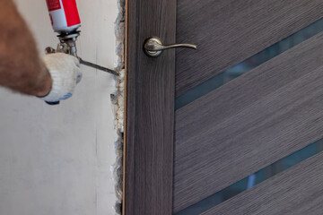 Installation of the door block. The worker fixes the door frame with foam.