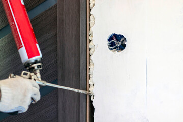 A master installing a door block using polyurethane foam in the room. - obrazy, fototapety, plakaty