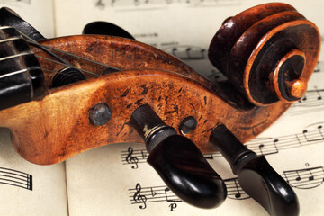 Violin scroll with pegs lies on violin notes, close-up, selective focus