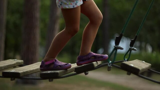 brave little girl having fun at adventure park. toddler climbing in a rope playground structure. Scout practicing rappelling