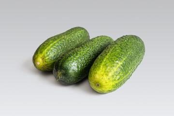 Three ripe cucumbers for salad on a light background