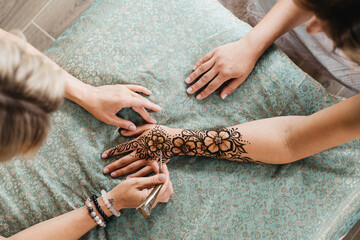 Artist applying henna tattoo on women hands. Mehndi is traditional Indian decorative art, Hand with...
