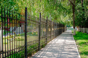 A beautiful forged metal fence along the alley in the city center.