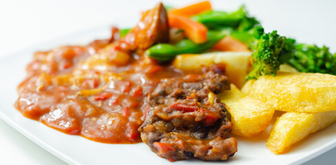 Pulled pork in barbecue style sauce with barbecues style beans with spiced chips and fresh vegetables