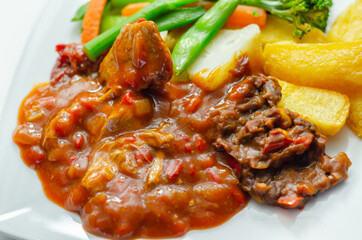 Pulled pork in barbecue style sauce with barbecues style beans with spiced chips and fresh vegetables
