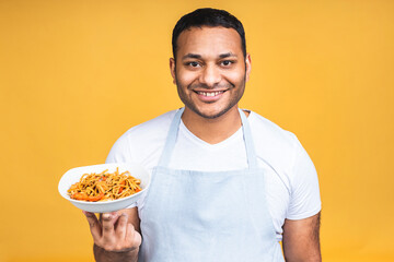 Portrait of of happy african american indian black man chef cooking pasta. Cooking, profession, haute cuisine, food and people concept isolated over yellow background.