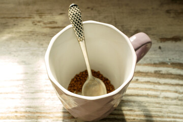 Pink mug with a teaspoon, at the bottom of the granule of instant coffee