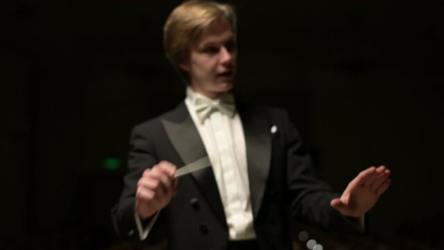 Close-up of a young conductor who begins to lead the orchestra