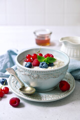 Oatmeal porridge with fresh berries and maple syrup for a breakfast.