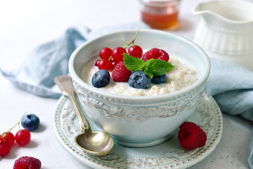 Oatmeal porridge with fresh berries and maple syrup for a breakfast.