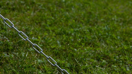 steel non-rusty chain on grass background, frame