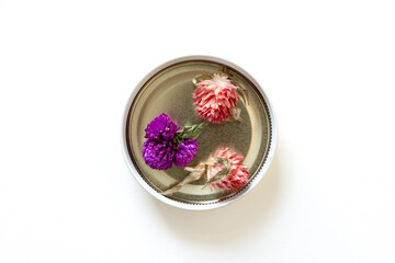pink and purple Gomphrena globosa in a metal container on a white background