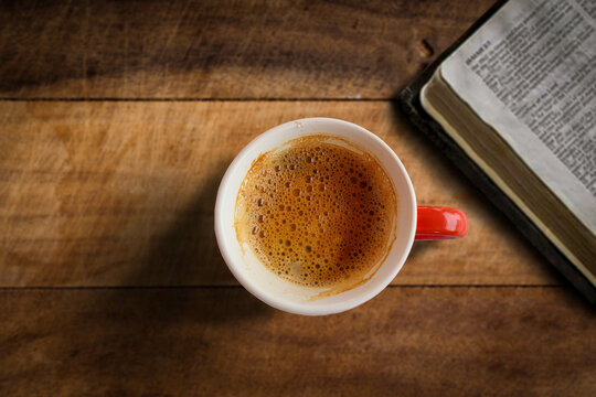 A picture of a coffee mug taken under controlled professional lighting on a wooden table beside a book.